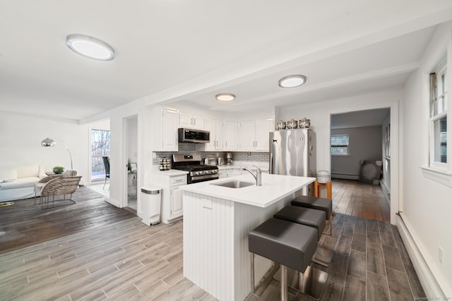 kitchen featuring appliances with stainless steel finishes, a kitchen breakfast bar, a kitchen island with sink, white cabinetry, and plenty of natural light