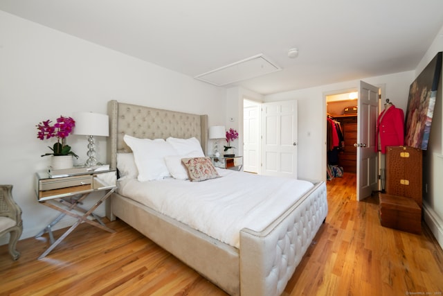 bedroom featuring a spacious closet, a closet, and light hardwood / wood-style flooring