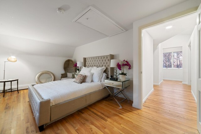 bedroom with light wood-type flooring, a baseboard radiator, and lofted ceiling