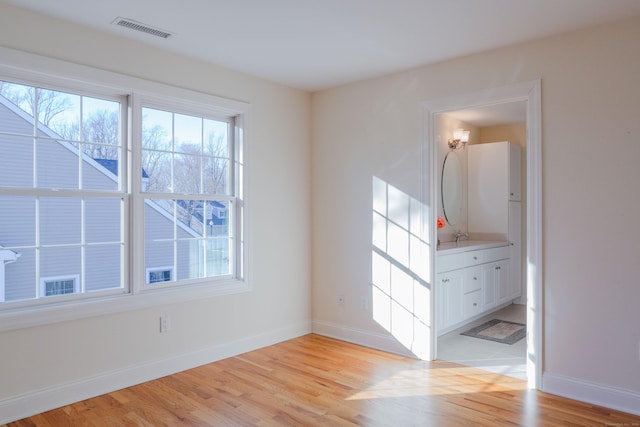 spare room with sink and light hardwood / wood-style floors