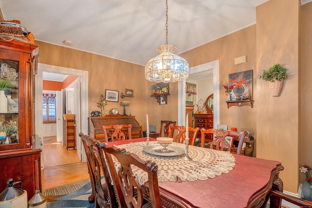 dining area featuring a notable chandelier, light hardwood / wood-style floors, and ornamental molding