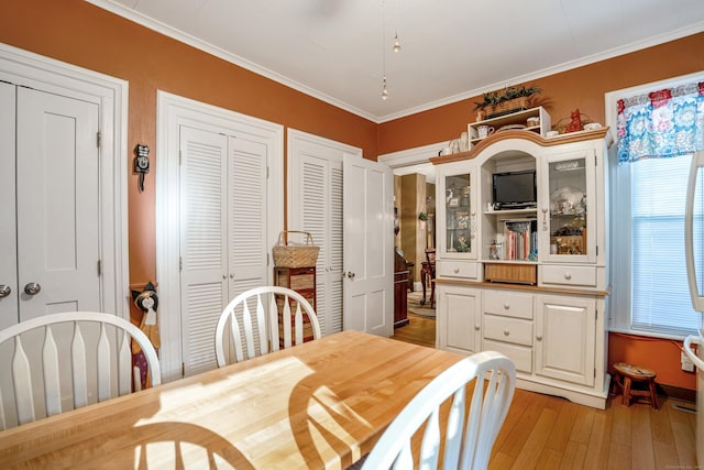 dining space featuring light wood-type flooring and crown molding