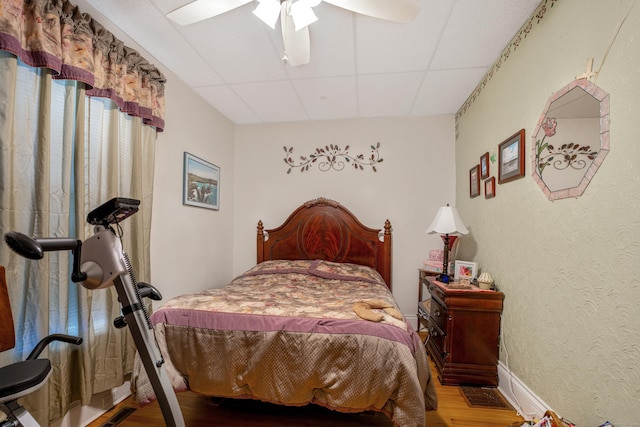 bedroom with a paneled ceiling, ceiling fan, and hardwood / wood-style floors