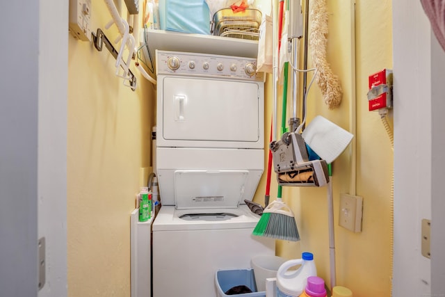 clothes washing area with stacked washing maching and dryer