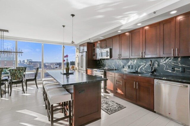 kitchen with premium appliances, a kitchen island, decorative light fixtures, sink, and a breakfast bar