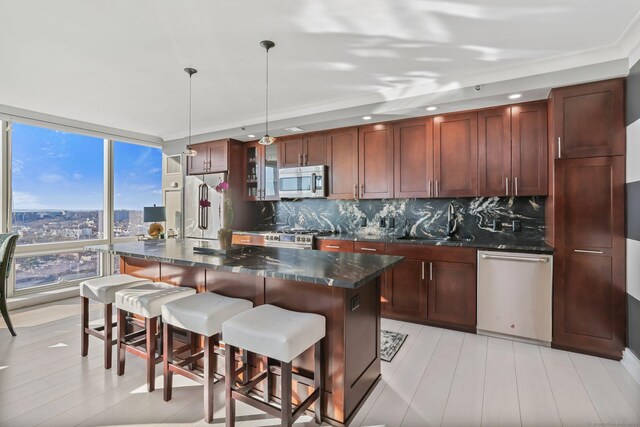 kitchen with stainless steel appliances, tasteful backsplash, hanging light fixtures, expansive windows, and a center island with sink