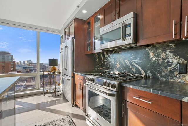 kitchen with decorative backsplash, light tile patterned floors, stainless steel appliances, and dark stone counters