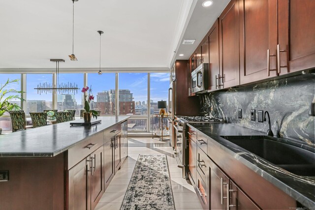 kitchen with appliances with stainless steel finishes, backsplash, a center island, hanging light fixtures, and sink