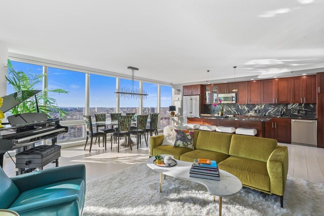 living room featuring a chandelier, a healthy amount of sunlight, a wall of windows, and light hardwood / wood-style flooring