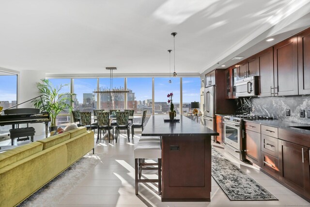 kitchen featuring decorative light fixtures, appliances with stainless steel finishes, a center island, and a kitchen bar