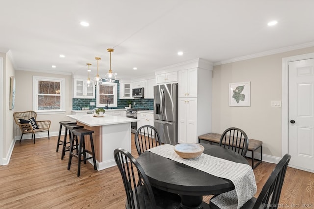 dining area with crown molding, sink, and light wood-type flooring