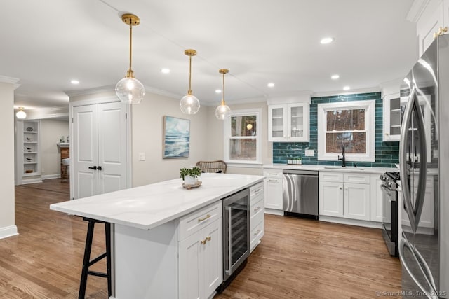 kitchen with appliances with stainless steel finishes, tasteful backsplash, pendant lighting, a center island, and white cabinetry