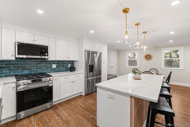 kitchen with decorative backsplash, stainless steel appliances, white cabinetry, and a kitchen island