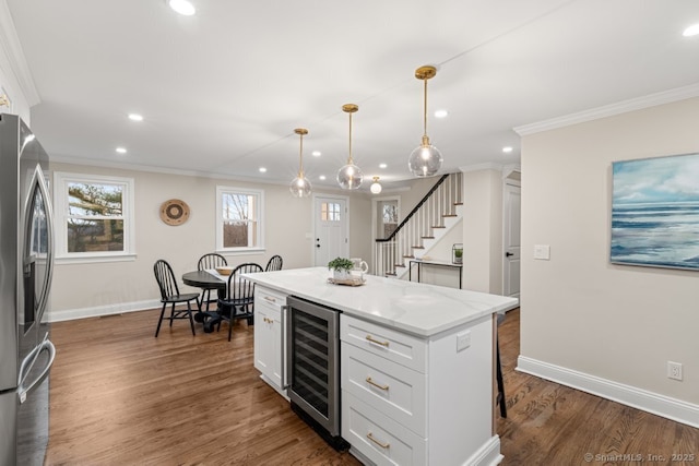 kitchen featuring stainless steel fridge, beverage cooler, decorative light fixtures, white cabinets, and a center island