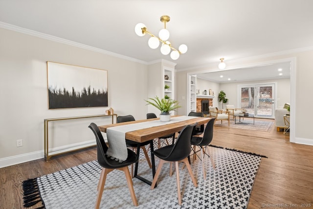 dining space with built in shelves, dark hardwood / wood-style floors, a brick fireplace, and ornamental molding