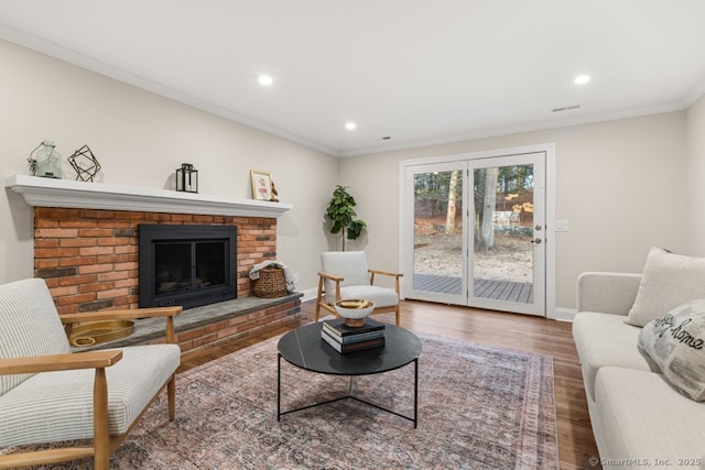 living room featuring a fireplace, wood-type flooring, and ornamental molding