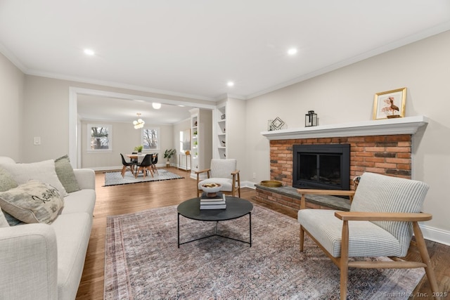 living room with hardwood / wood-style floors, ornamental molding, and a brick fireplace