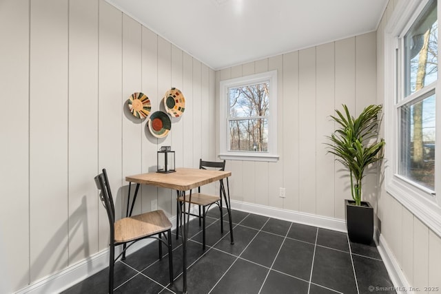 dining room with dark tile patterned flooring and wooden walls