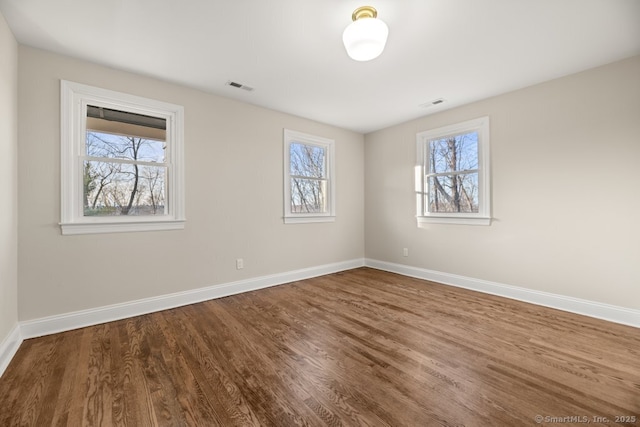 spare room with wood-type flooring and a wealth of natural light