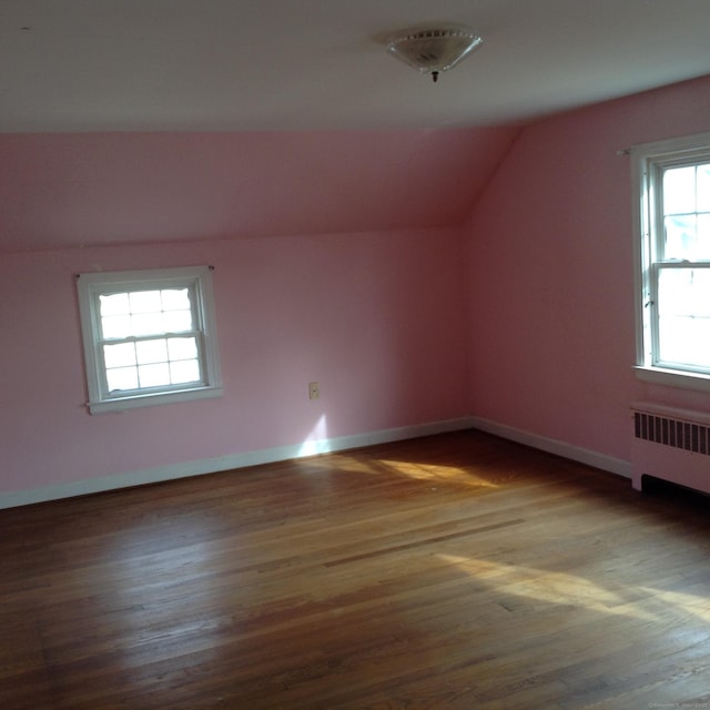 additional living space with lofted ceiling, radiator heating unit, and dark hardwood / wood-style flooring