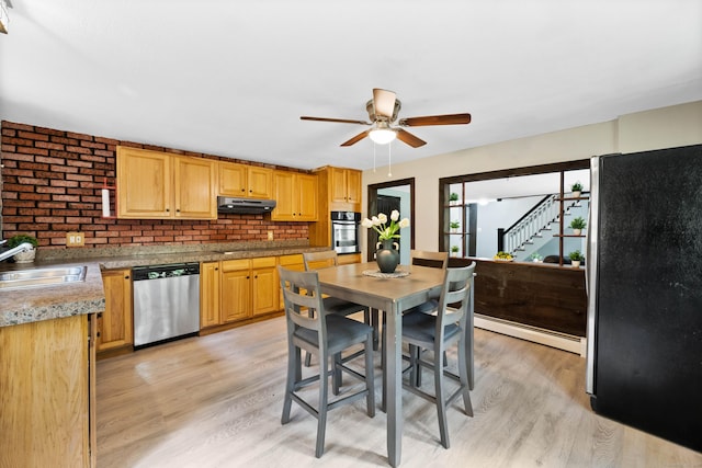 kitchen featuring sink, stainless steel appliances, baseboard heating, backsplash, and light wood-type flooring