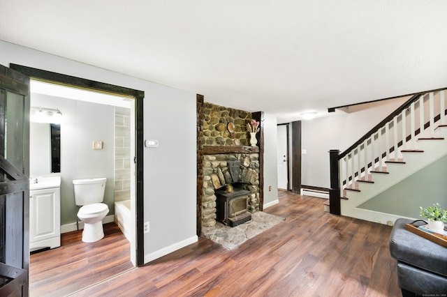 living room featuring dark hardwood / wood-style floors, a wood stove, and a baseboard heating unit