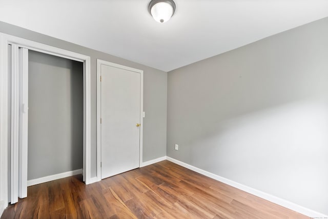 unfurnished bedroom featuring a closet and dark hardwood / wood-style flooring