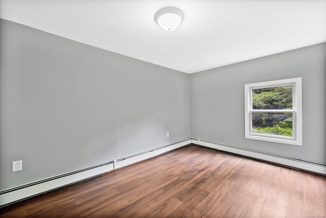 empty room with hardwood / wood-style flooring and a baseboard heating unit