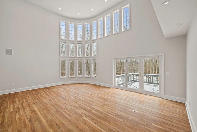 spare room featuring a high ceiling and light hardwood / wood-style flooring