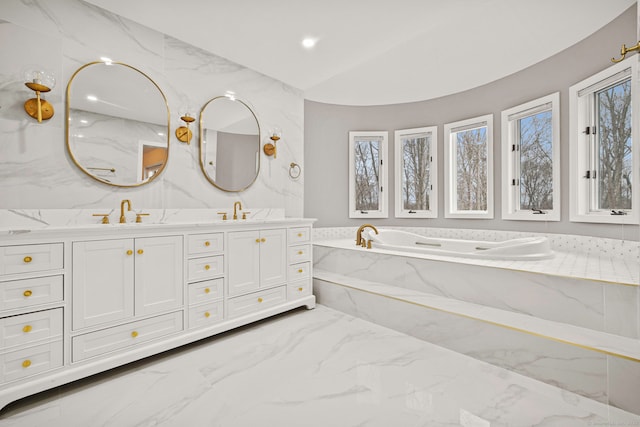 bathroom featuring vanity, vaulted ceiling, and tiled bath