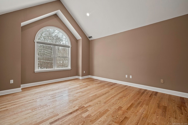 empty room with light hardwood / wood-style flooring and lofted ceiling