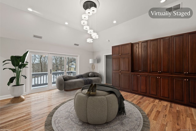 living room with french doors, vaulted ceiling, and light hardwood / wood-style floors