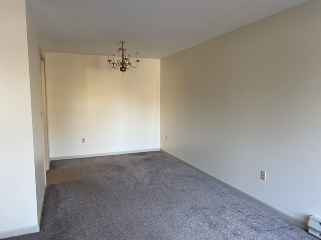 carpeted spare room featuring a chandelier