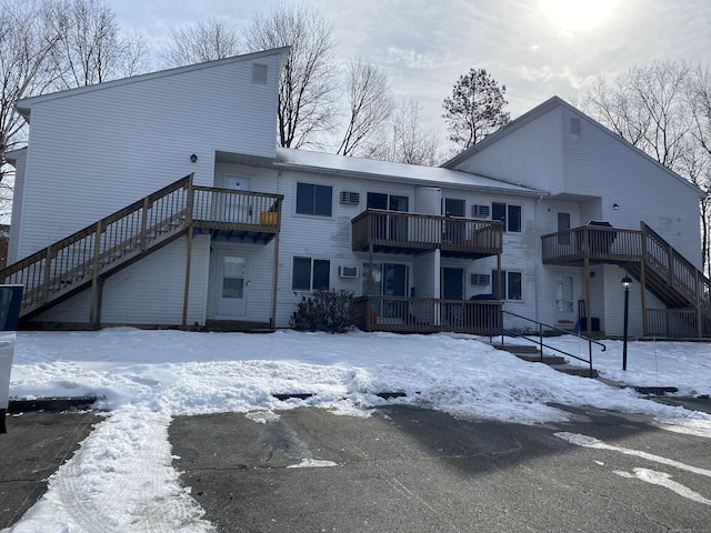 snow covered property featuring a wooden deck and a balcony