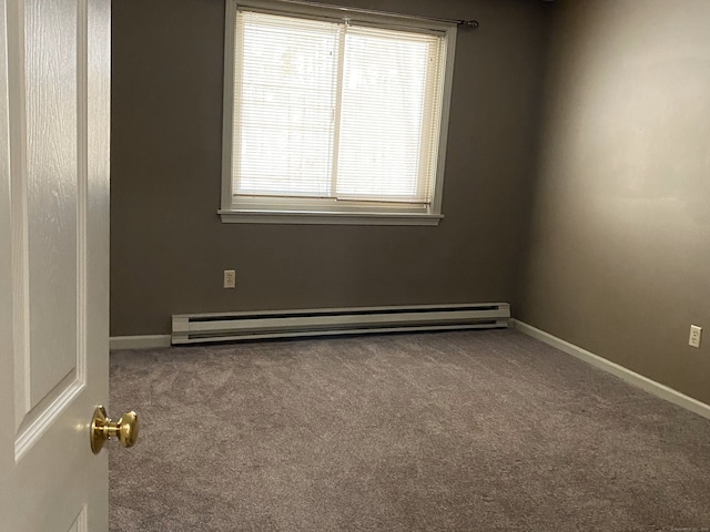 carpeted empty room featuring a baseboard heating unit