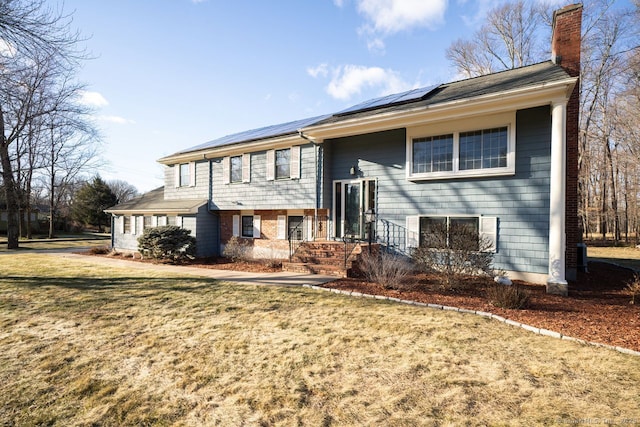 split foyer home featuring solar panels and a front lawn