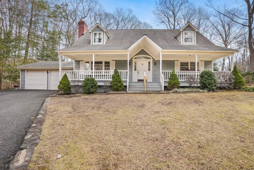 cape cod-style house with covered porch, a front lawn, and a garage