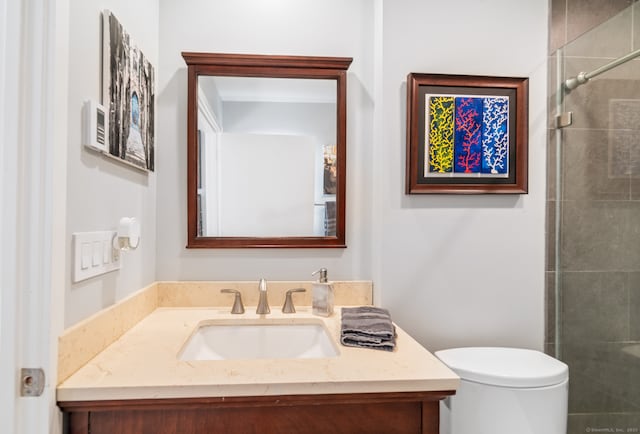 bathroom with tiled shower, vanity, and toilet