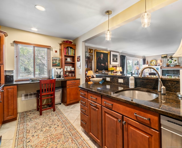 kitchen featuring light tile patterned floors, decorative light fixtures, dark stone countertops, and sink