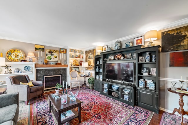 living room with crown molding, a fireplace, hardwood / wood-style floors, and built in features