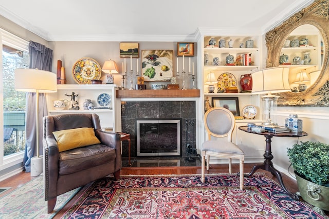 sitting room featuring ornamental molding, hardwood / wood-style flooring, a healthy amount of sunlight, and a tiled fireplace