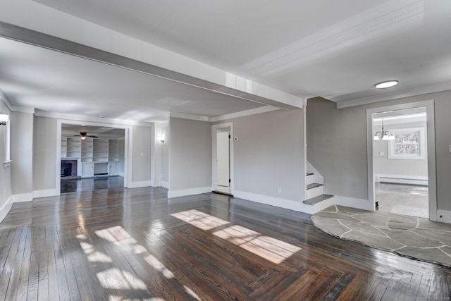 unfurnished living room featuring dark wood-type flooring, ceiling fan with notable chandelier, and a baseboard heating unit