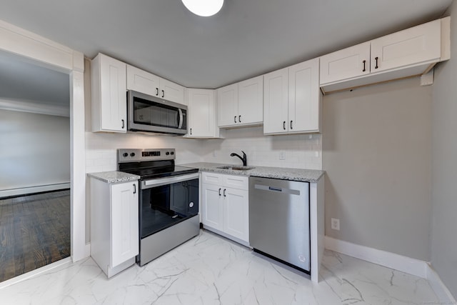 kitchen featuring stainless steel appliances, light stone countertops, decorative backsplash, and white cabinets