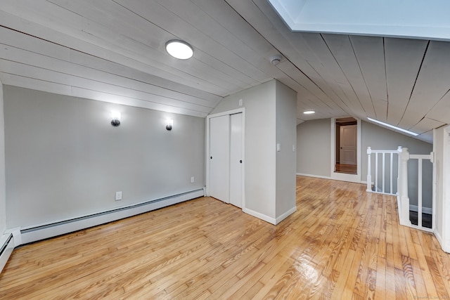 additional living space with baseboard heating, vaulted ceiling, and light wood-type flooring