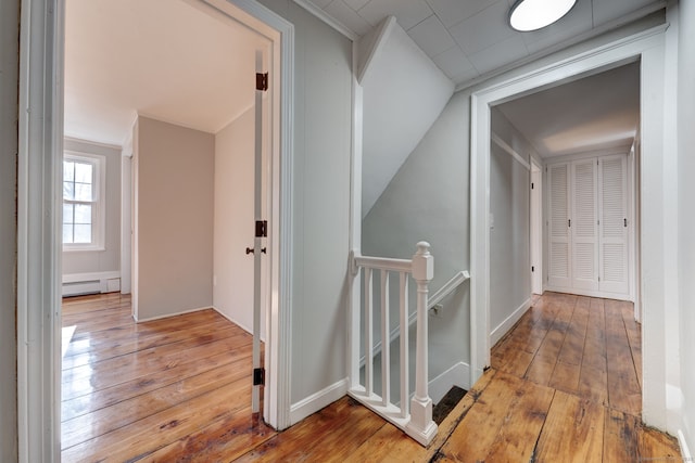 corridor featuring a baseboard heating unit and light hardwood / wood-style floors