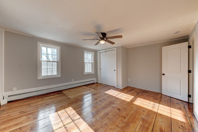unfurnished bedroom featuring baseboard heating, ornamental molding, and light wood-type flooring