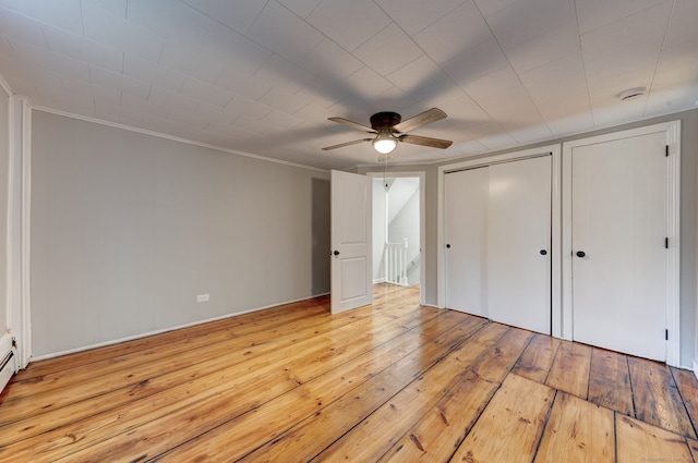 unfurnished bedroom with multiple closets, crown molding, ceiling fan, and light hardwood / wood-style flooring