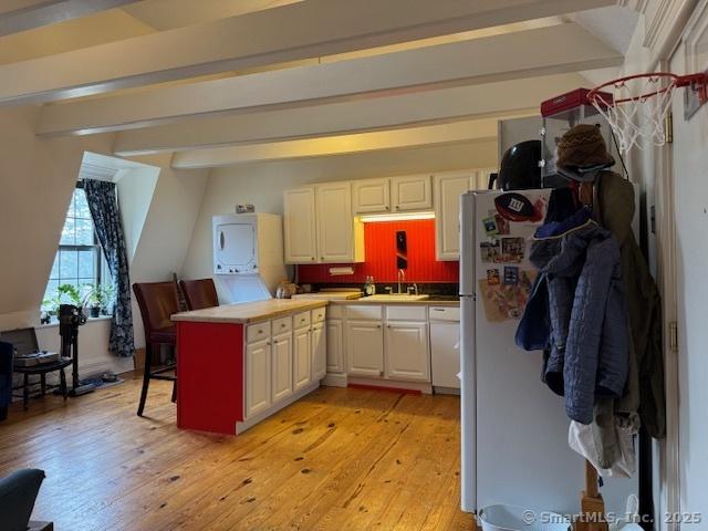 kitchen featuring beamed ceiling, white cabinets, and light wood-type flooring