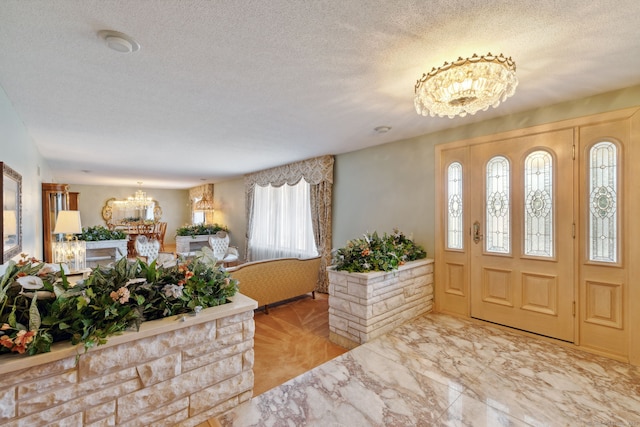 entryway featuring light parquet flooring, a textured ceiling, and a chandelier