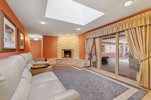 living room featuring a skylight and a stone fireplace